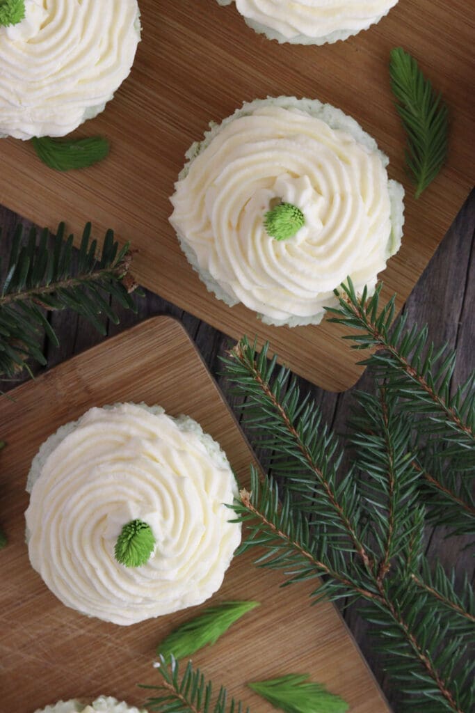 Image of four mini spruce tip cakes on a wooden plate.